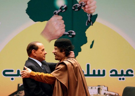 Thủ tướng Italy Silvio Berlusconi ôm ông Gaddafi tại Sirte. Tháng 3/2009, ông Berlusconi đến Libya ký hiệp ước đền bù cho thời gian đô hộ kéo dài 32 năm (1911-1943) của Italy đối với Libya.